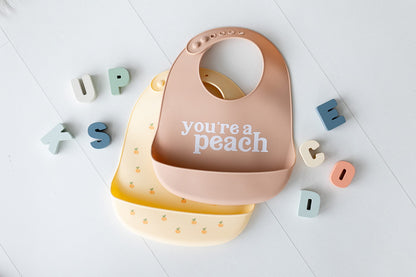 Pearhead Silicone Bib Set of 2, You're a Peach & Light Yellow Waterproof Bibs with Food Catcher, Adjustable Fit, Dishwasher Safe, Unisex Toddler Bib Set